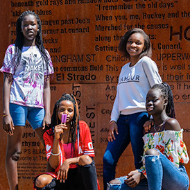 Four teen girls with popsicles posing in front of Halifax North's landmark sign on a sunny summer day