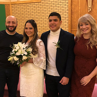 A bride and groom posing with two friends, smiling